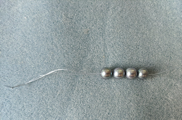 Step 6: Pearls positioned near the end of the thread.