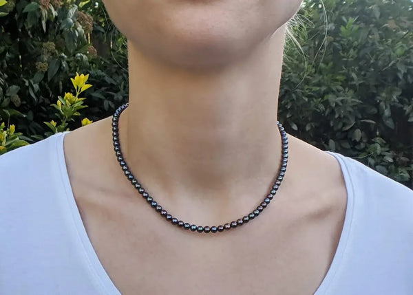 Black beaded necklace showcasing elegant black freshwater pearls around a neck.