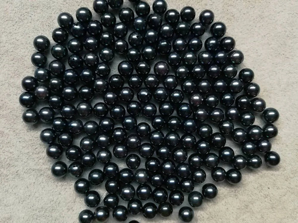 Collection of shiny black spherical beads including Black Freshwater Pearls and Tahitian Pearls.