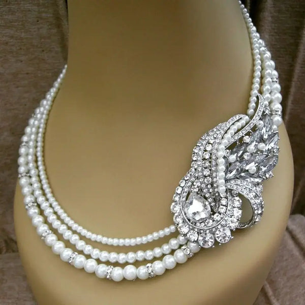 Elegant pearl necklace featuring a Swarovski crystal brooch accent on one side.