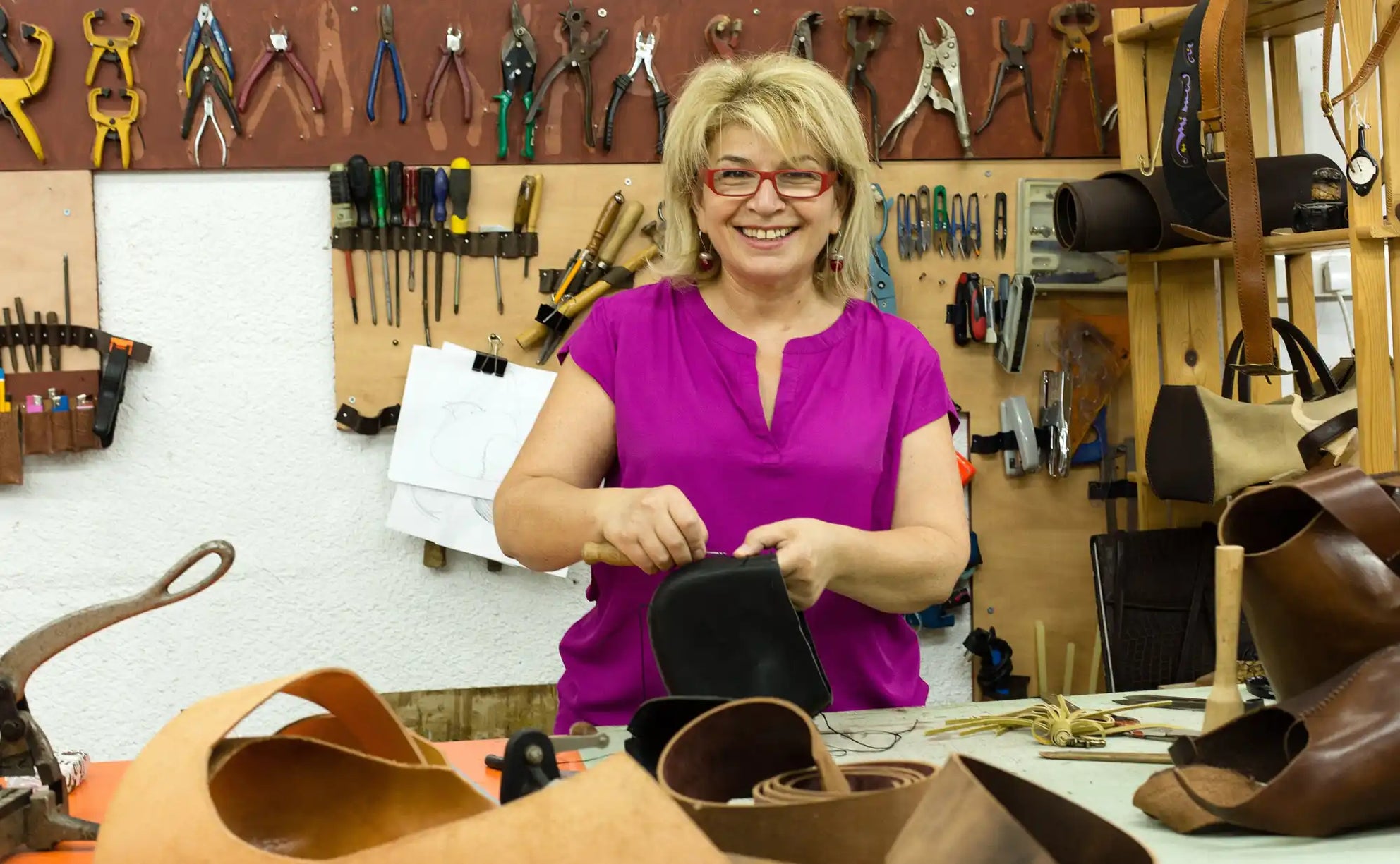 Someone working with leather materials and tools in a crafting workshop.