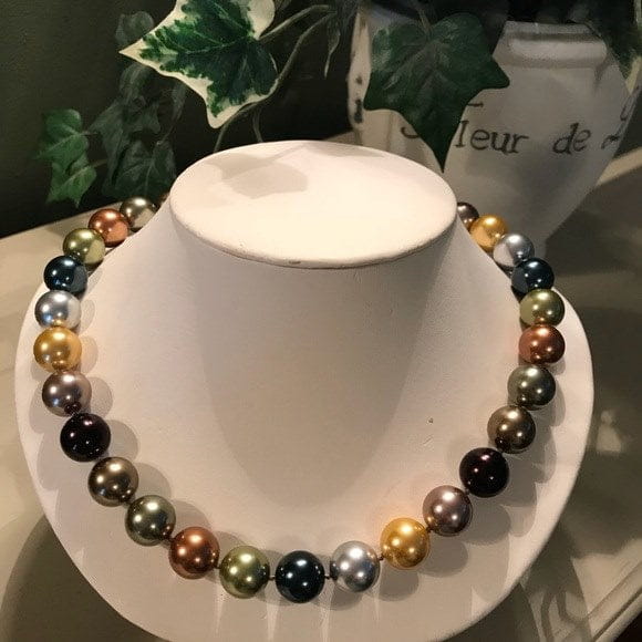 Multi-colored pearl necklace on white stand to differentiate real pearls from fake ones