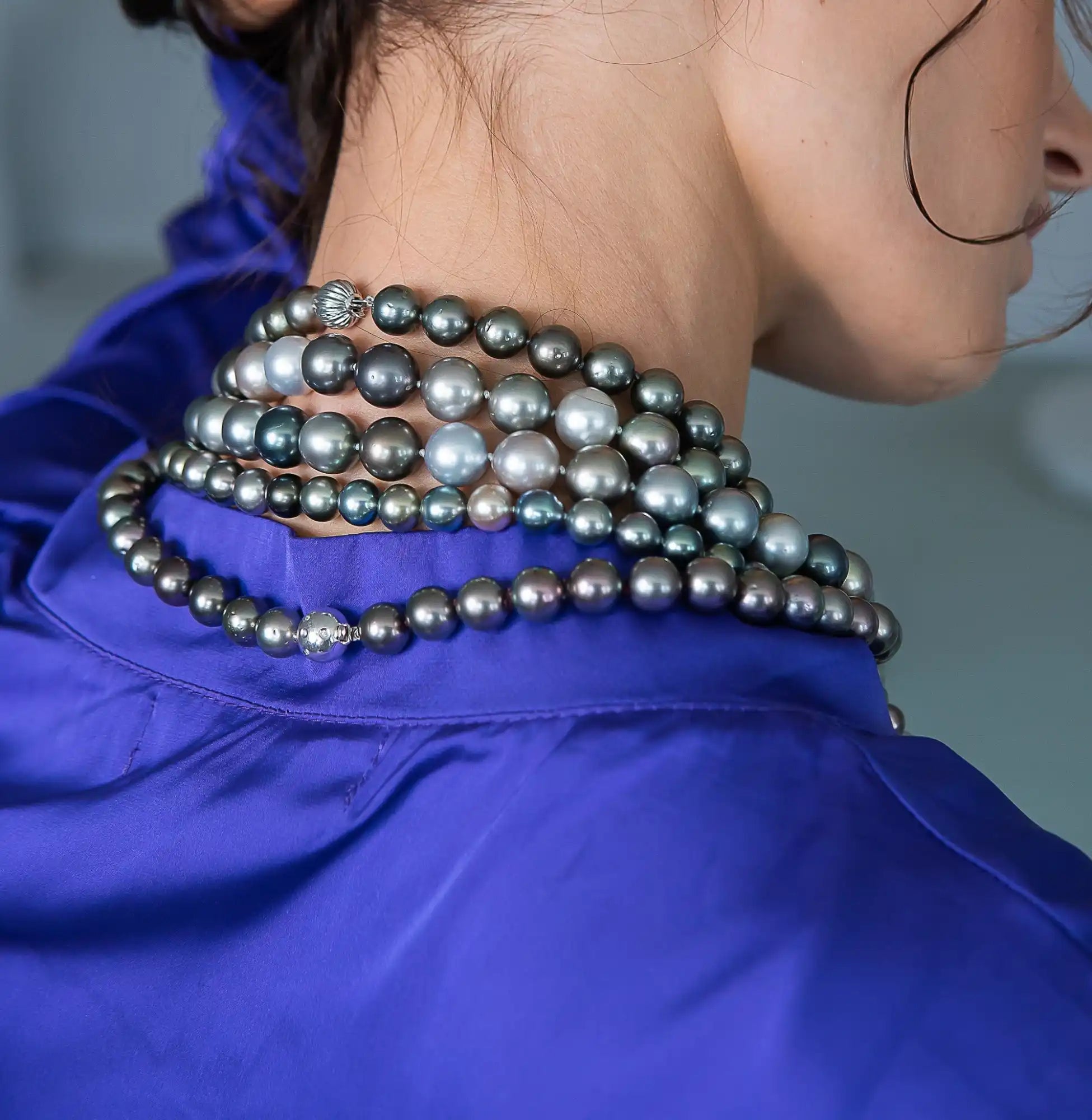 Multi-strand pearl necklace draped over a royal blue collar.