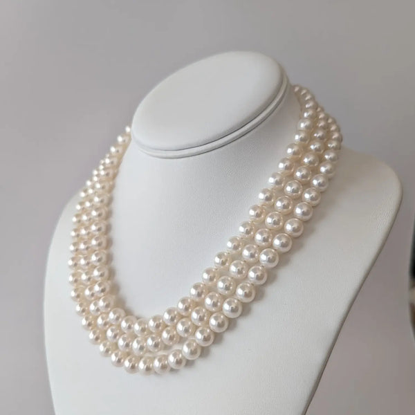 Multi-strand pearl necklace of white Akoya pearls on a white jewelry bust.