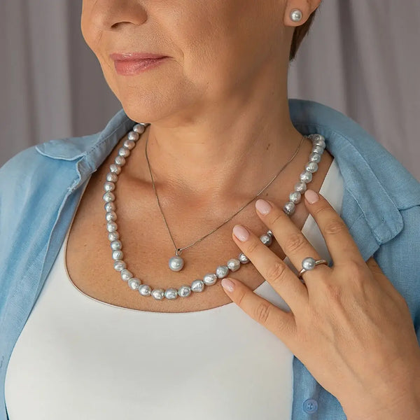 Pearl necklace and earrings with rings paired with a blue shirt featuring blue Akoya pearls.