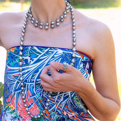 Pearl necklace with tropical dress showcasing essential pearl care tips for summer.