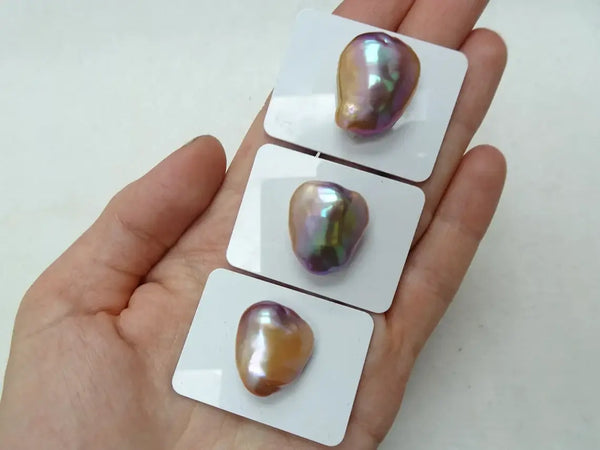 Three iridescent cultured soufflé pearls on white display cards by Marina Korneev