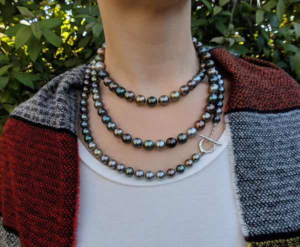 Triple-strand necklace featuring iridescent Tahitian pearls in a black pearl guide.