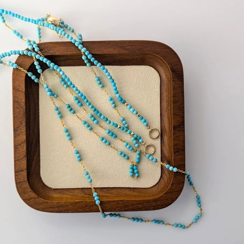 Turquoise beaded necklace draped across a wooden frame.