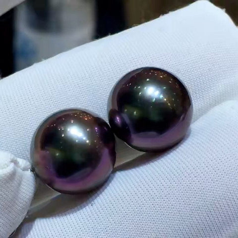 Two iridescent black Tahitian pearls with stunning purple undertones showcased elegantly.