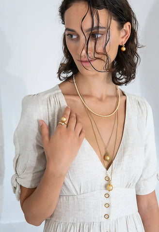 White cotton dress with gold buttons and a plunging neckline.