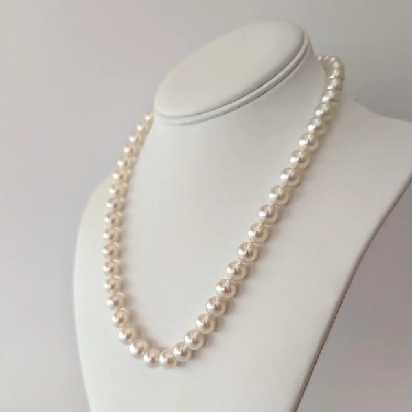 White Akoya pearls necklace with a pink overtone on a stylish jewelry stand.